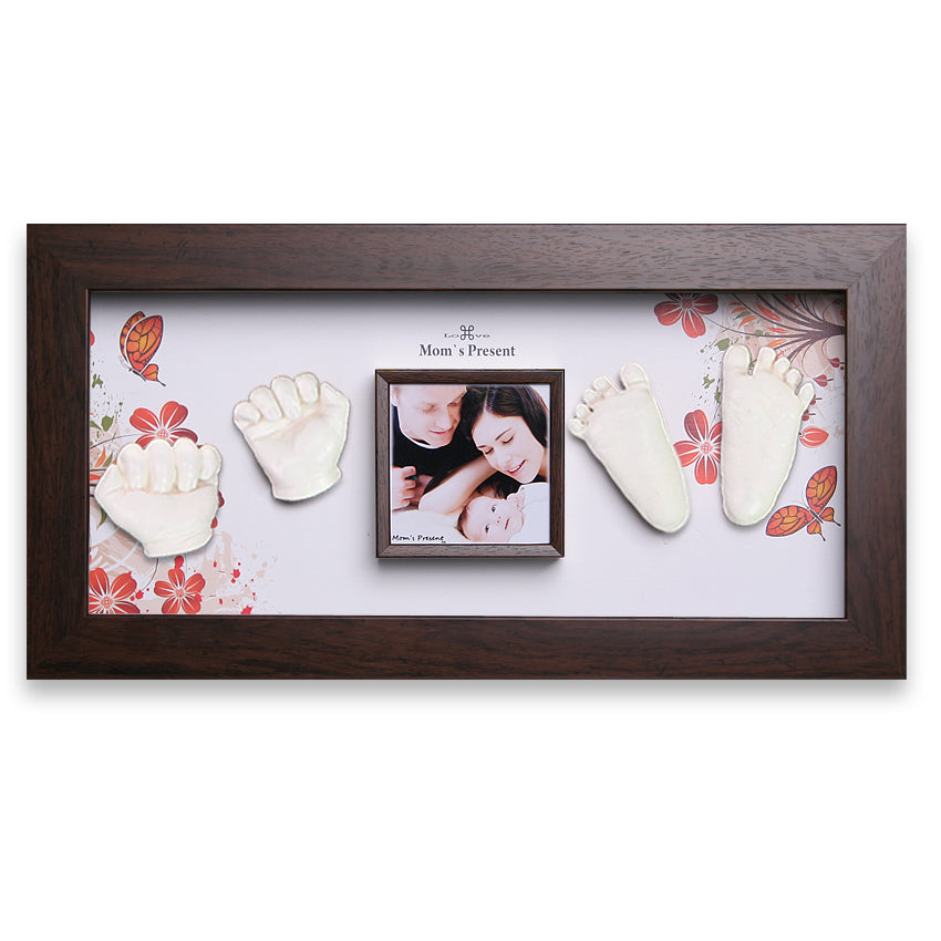 A luxury baby memory kit featuring two small handprints and footprints in plaster, positioned around a central square photo of a smiling family. The background has floral accents, and “Mom’s Present” is written above the photo. This custom baby gift captures precious moments beautifully. Introducing the Momspresent Baby Hands and Foot Casting 3D Print DIY Kit with Walnut Frame1- The spring of life by LOVE MOM'S PRESENT.