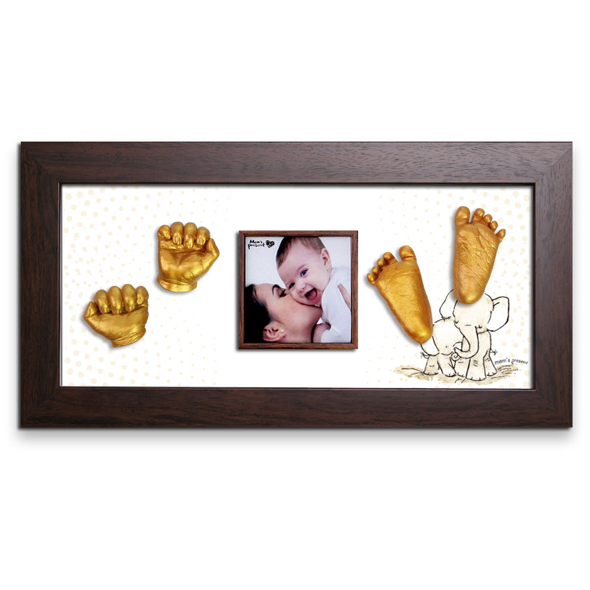 A luxury photo frame featuring a smiling baby and an adult, surrounded by golden casts from the LOVE MOM'S PRESENT Momspresent Baby Hands and Foot 3D Casting Print DIY Kit with Walnut Frame8-Elephant-Hug. The background includes a playful illustration of an elephant, with "LOVE MOM'S PRESENT" tastefully inscribed on the dark wood frame.